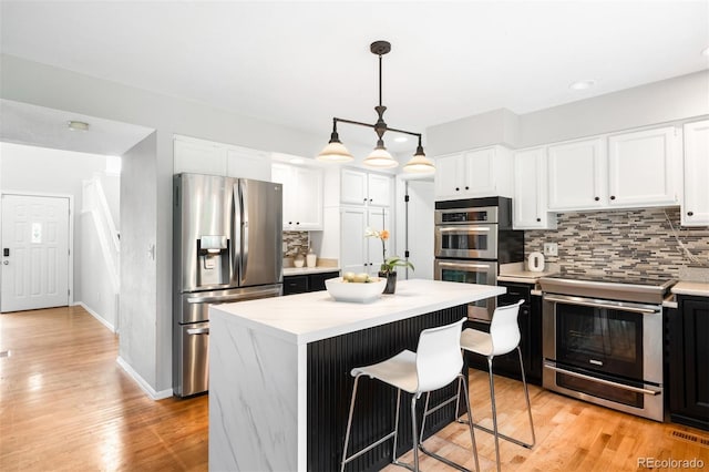 8288 W Chestnut Ave, Littleton, CO 80128 - kitchen with stainless steel appliances, decorative backsplash, light countertops, white cabinetry, and recessed lighting