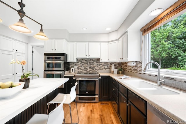 8288 W Chestnut Ave, Littleton, CO 80128 - kitchen with stainless steel appliances, white cabinets, light countertops, light wood finished floors, and recessed lighting