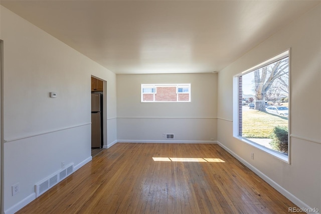 empty room featuring visible vents, baseboards, and hardwood / wood-style floors