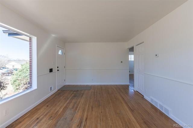 unfurnished room with visible vents, wood-type flooring, and baseboards