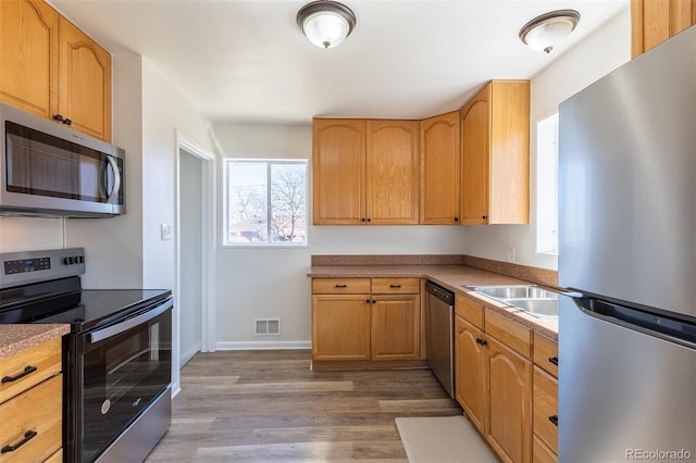 kitchen with baseboards, visible vents, a sink, appliances with stainless steel finishes, and light wood-type flooring