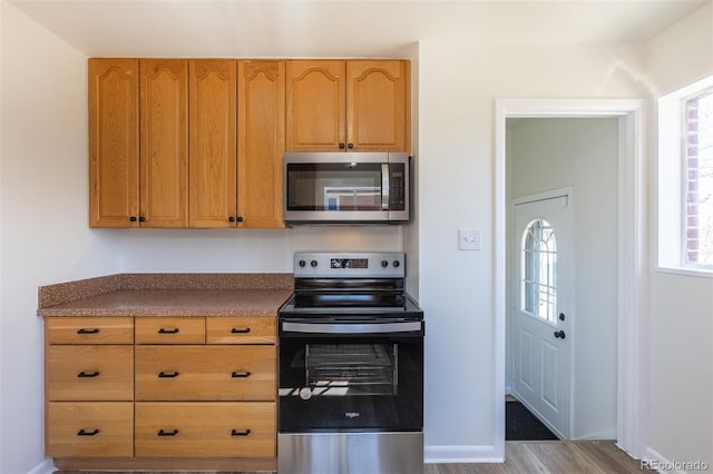 kitchen featuring dark countertops, appliances with stainless steel finishes, baseboards, and wood finished floors