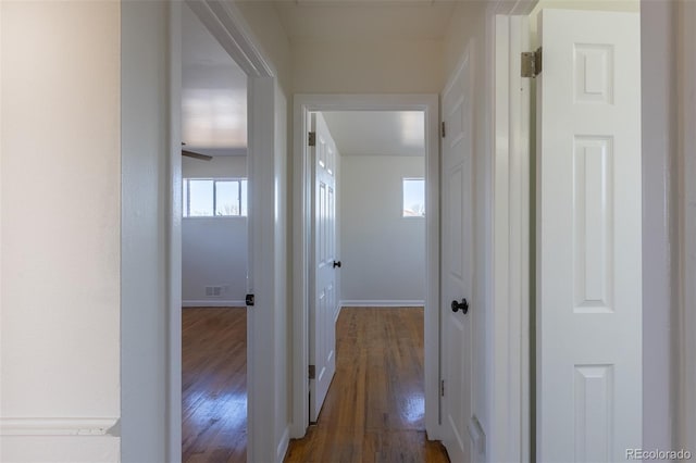 hall with visible vents, baseboards, and dark wood-style flooring