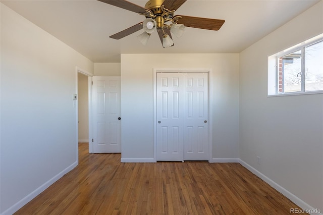 unfurnished bedroom with ceiling fan, a closet, baseboards, and wood finished floors