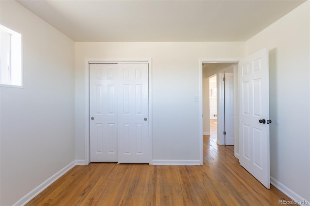 unfurnished bedroom with wood finished floors, baseboards, and a closet