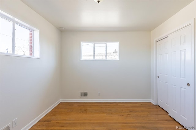 unfurnished bedroom with multiple windows, visible vents, and light wood finished floors