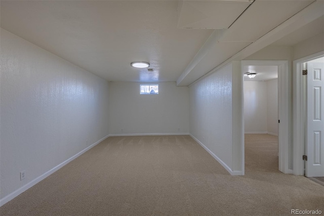 basement featuring baseboards and light colored carpet