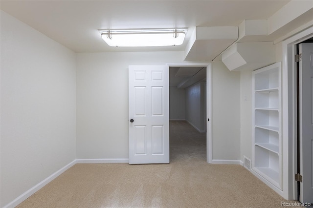 below grade area with light carpet, visible vents, and baseboards