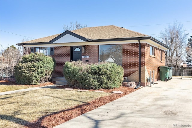 view of front of house with fence, brick siding, and a shingled roof