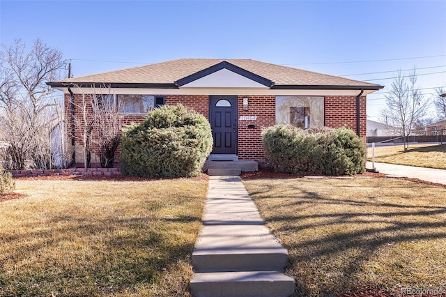 bungalow with brick siding, a front lawn, and a shingled roof