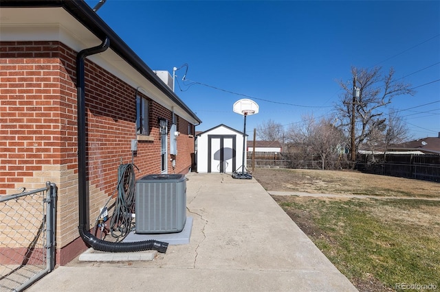 view of yard featuring a storage unit, central air condition unit, an outbuilding, and fence