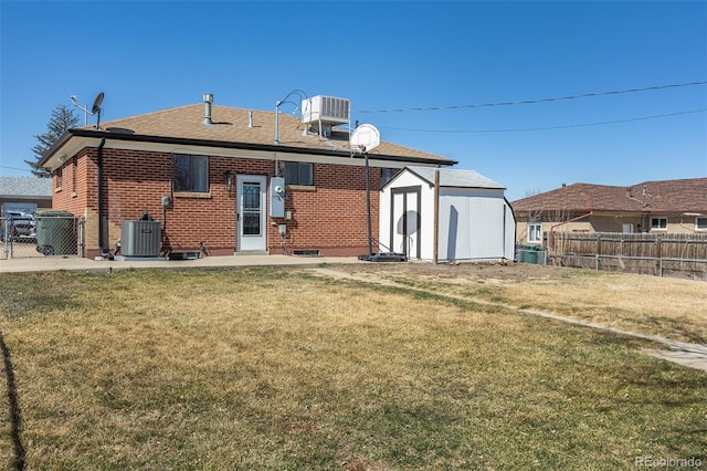 rear view of property with brick siding, central AC unit, a yard, and fence