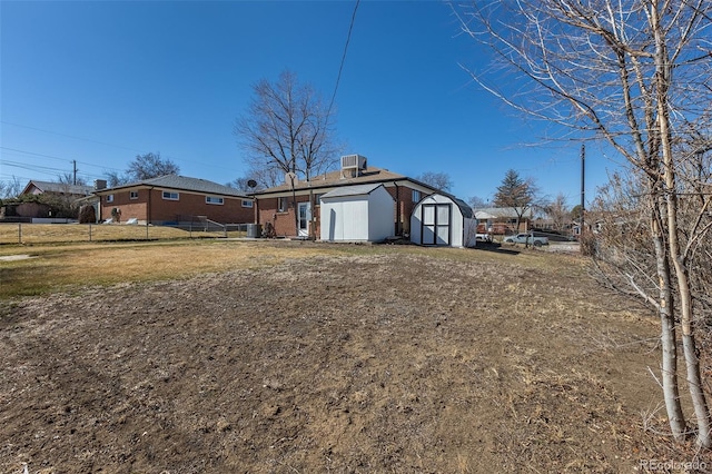 exterior space featuring brick siding, a shed, a front lawn, and an outdoor structure