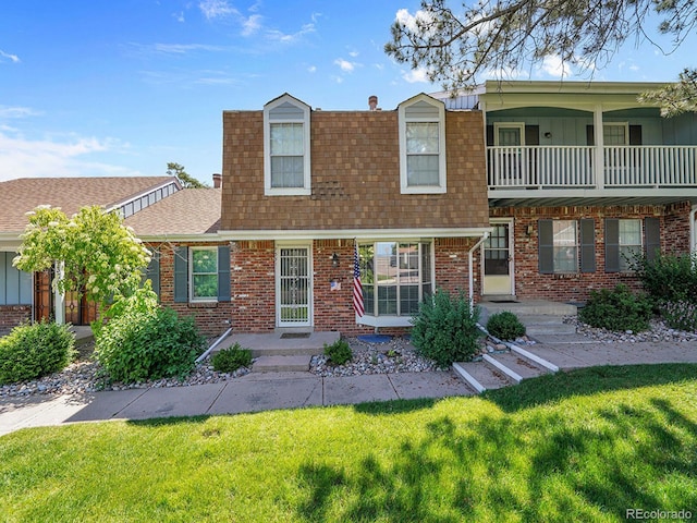 7391 S Knolls Way, Centennial, CO 80122 - view of front of house featuring roof with shingles, a front yard, brick siding, and a balcony