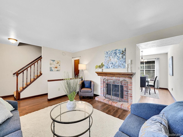 7391 S Knolls Way, Centennial, CO 80122 - living area with stairs, wood finished floors, a brick fireplace, and a chandelier