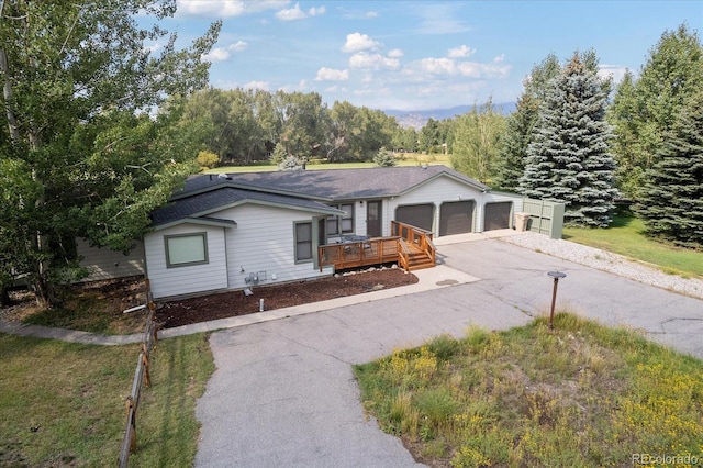 view of front facade with a garage, a front lawn, and a deck