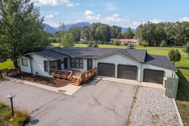 single story home featuring a mountain view, a garage, covered porch, and a front lawn