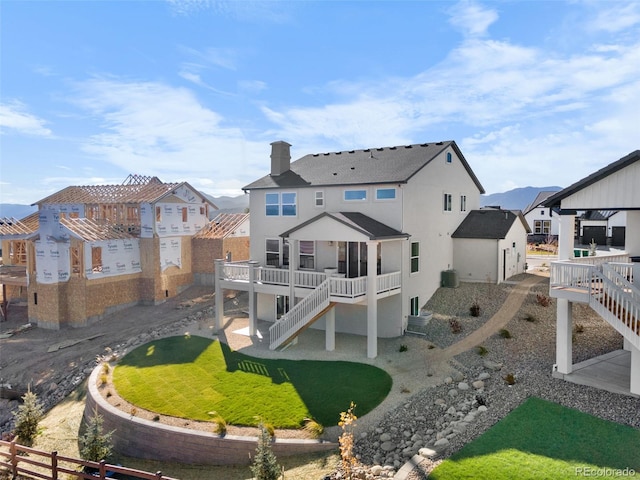 rear view of house featuring stucco siding, stairs, fence, a wooden deck, and a chimney