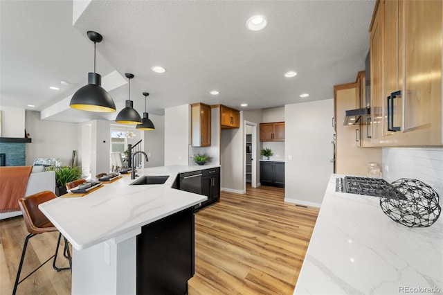 kitchen with a sink, light wood-style floors, a peninsula, and open floor plan