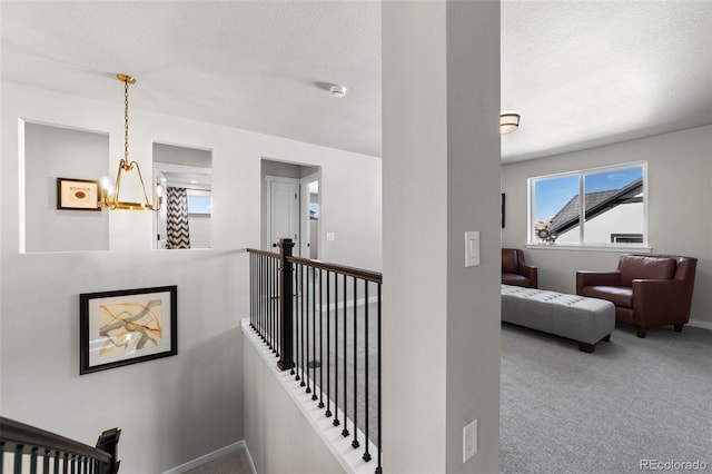 staircase with baseboards, carpet floors, a notable chandelier, and a textured ceiling