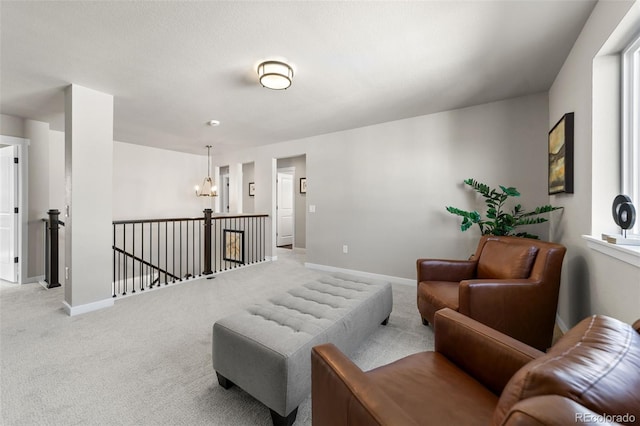 carpeted living room featuring baseboards and an inviting chandelier