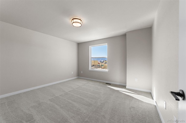 unfurnished room with visible vents, baseboards, and light carpet