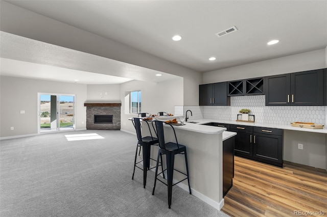 kitchen with visible vents, light countertops, a kitchen bar, a fireplace, and a sink