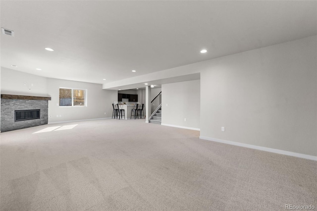 unfurnished living room featuring visible vents, baseboards, a fireplace, stairs, and carpet flooring