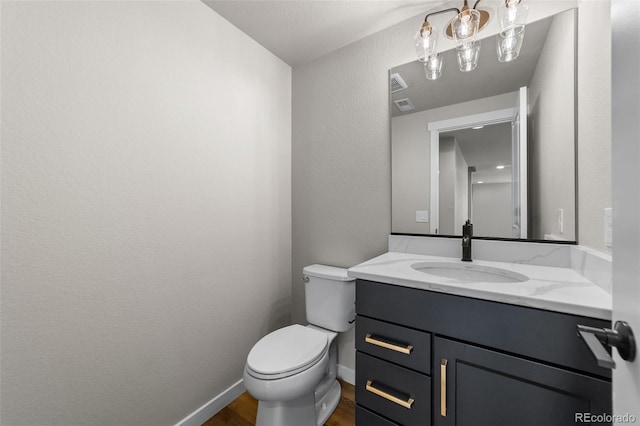 half bathroom featuring visible vents, toilet, wood finished floors, baseboards, and vanity