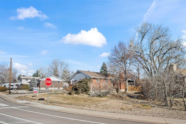 view of road featuring traffic signs, a residential view, curbs, and sidewalks