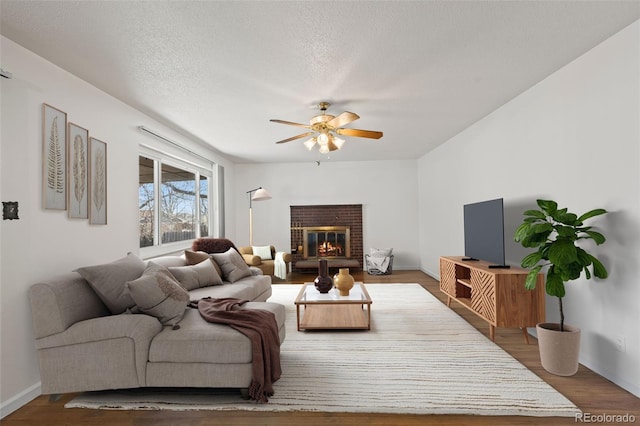 343 Melody Dr, Northglenn, CO 80260 - living room featuring wood finished floors, a ceiling fan, a brick fireplace, a textured ceiling, and baseboards