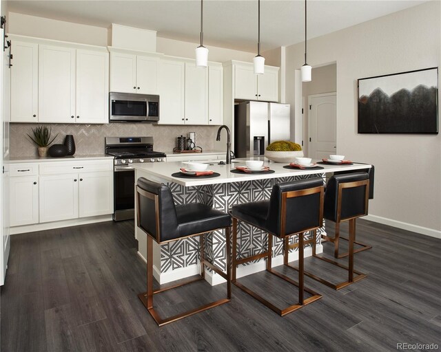 kitchen featuring appliances with stainless steel finishes, a sink, dark wood-style floors, tasteful backsplash, and white cabinetry