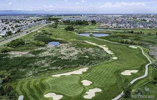 aerial view of property's location with a large body of water, a golf course, and nearby suburban area