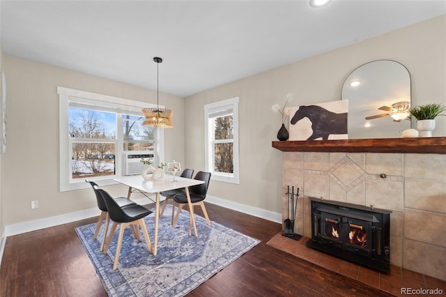 dining area with a tile fireplace, plenty of natural light, and dark hardwood / wood-style flooring