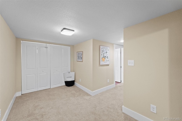 unfurnished bedroom featuring light colored carpet, a textured ceiling, and a closet