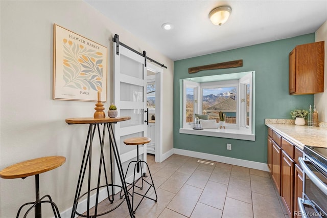 kitchen with a barn door, light tile patterned floors, and electric range