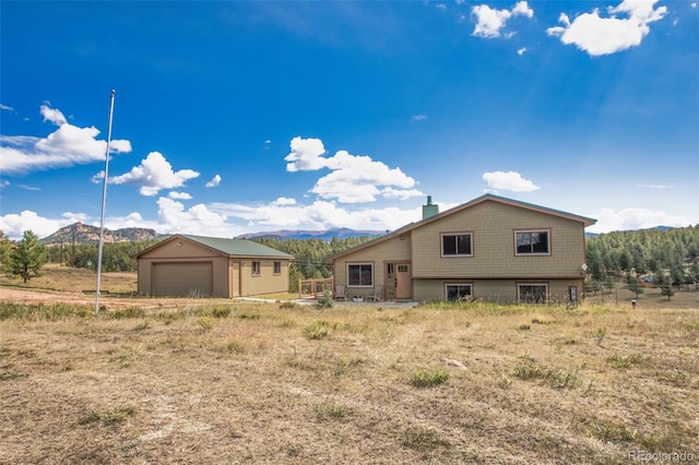 rear view of house featuring a garage, a mountain view, and an outbuilding