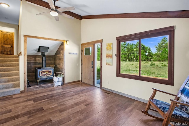 unfurnished living room featuring ceiling fan, lofted ceiling, a wood stove, and dark hardwood / wood-style floors