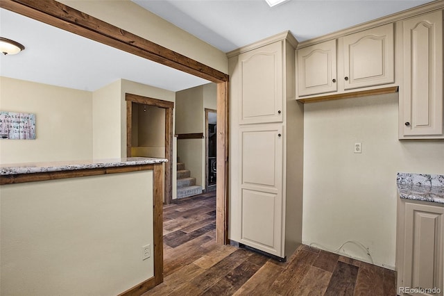 kitchen featuring dark hardwood / wood-style flooring, light stone counters, and cream cabinetry