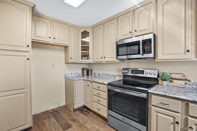 kitchen featuring cream cabinets, light stone countertops, and appliances with stainless steel finishes