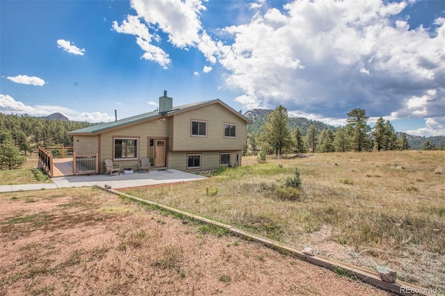 back of property with a mountain view and a patio area