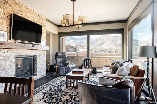 living area featuring a chandelier, a fireplace, wood finished floors, and ornamental molding