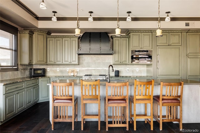 kitchen featuring premium range hood, oven, backsplash, and a sink