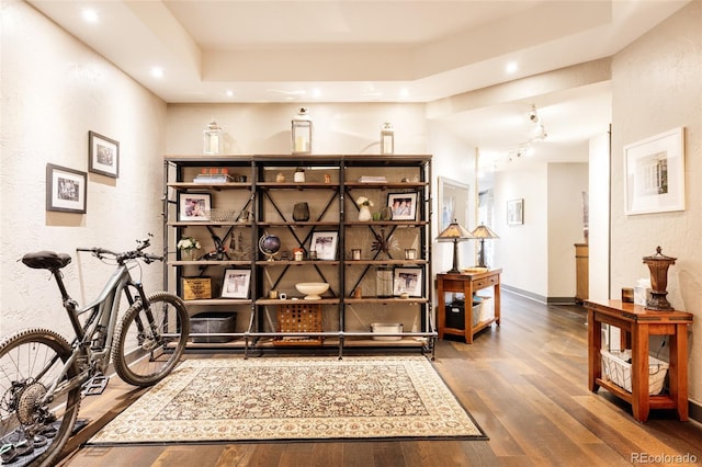 living area featuring recessed lighting, a raised ceiling, baseboards, and wood finished floors