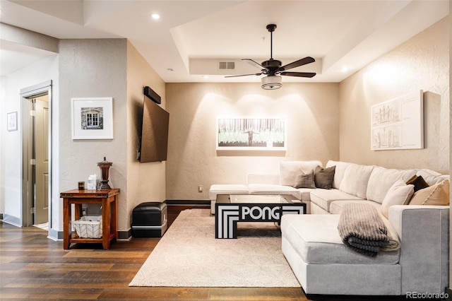 living area featuring baseboards, a raised ceiling, ceiling fan, and dark wood-style flooring