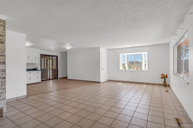 207 Autobee Ln, Avondale, CO 81022 - unfurnished living room featuring a textured ceiling, light tile patterned floors, and baseboards