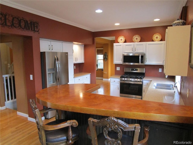 10522 Stoneflower Dr, Parker, CO 80134 - kitchen featuring stainless steel appliances, light wood-type flooring, ornamental molding, white cabinetry, and light countertops