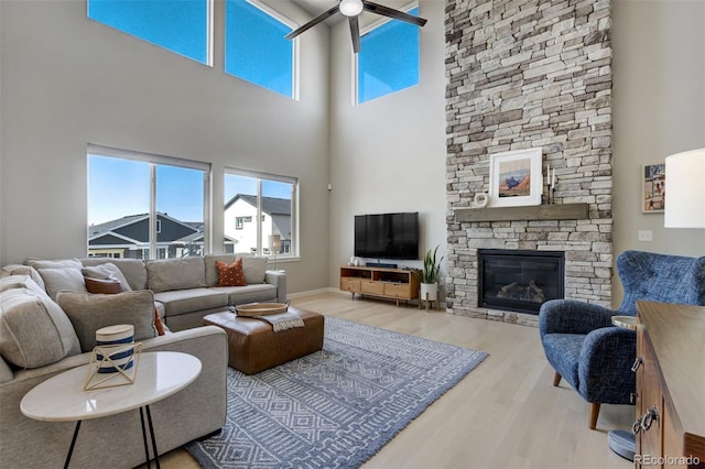 10024 Waterton Canyon Way, Colorado Springs, CO 80924 - living room featuring a towering ceiling, a stone fireplace, a ceiling fan, and wood finished floors