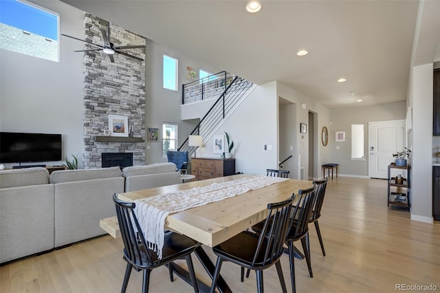 10024 Waterton Canyon Way, Colorado Springs, CO 80924 - dining room featuring a stone fireplace, a ceiling fan, stairway, and light wood finished floors