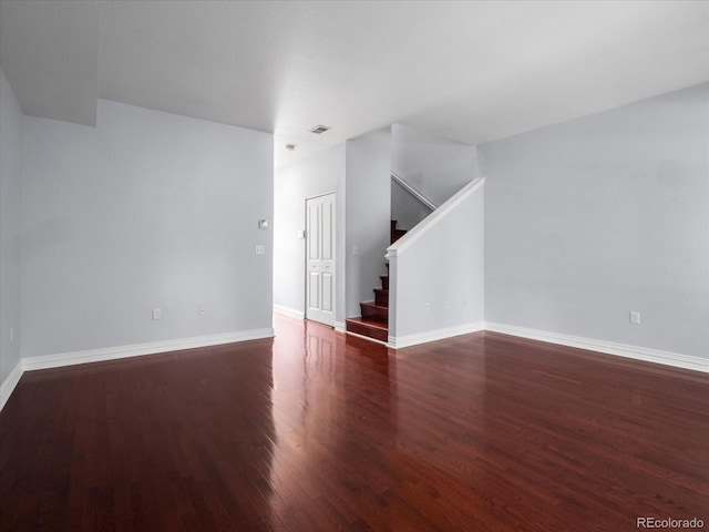 empty room with visible vents, stairs, baseboards, and wood finished floors